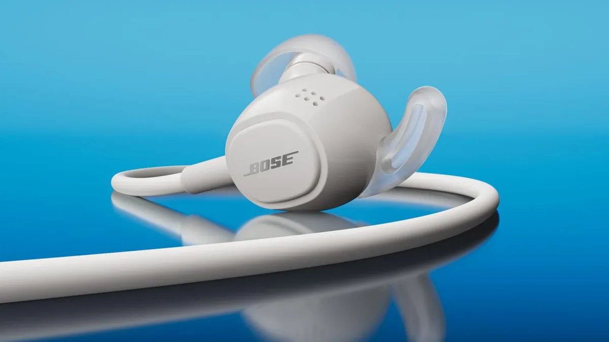 Een wit oordopje van de Bose Noise Cancelling Wired Earbuds met kabel op een blauwe achtergrond